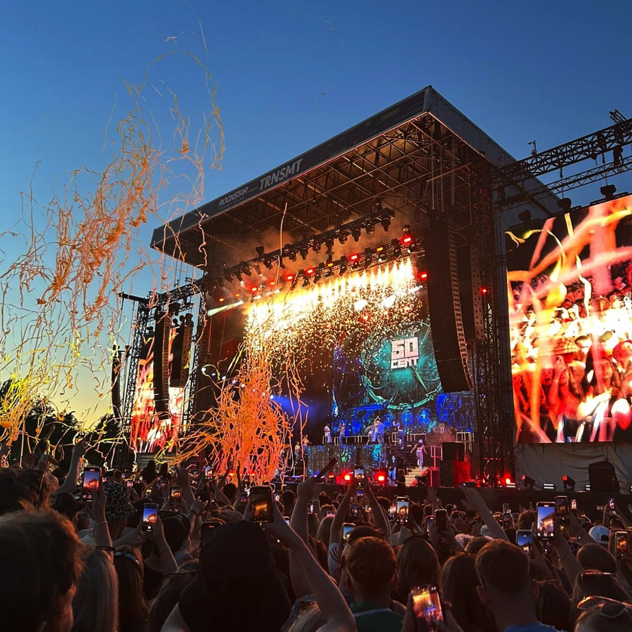 50 Cent live at the TRNSMT festival, surrounded by people dancing, and streamers in the air